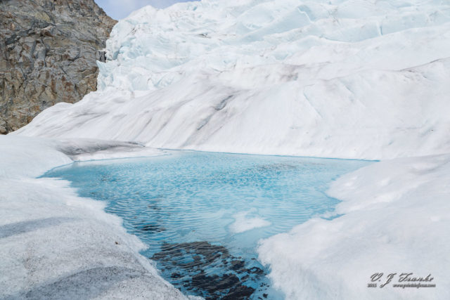 One of the many pools melt water on top a glacier. note dark sediment in foreground, this is pulverized rock that's been crushed by glacier.